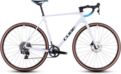 Das CUBE Cross Race C:62 Race polarwhite'n'blue 2025 ist ein Cyclocross-Rad mit schwarzen und blauen Akzenten, Sram Rival AXS, abnehmbarem Lenker, Scheibenbremsen und hellbraunen Seitenwandreifen. Abgebildet in der Seitenansicht auf weißem Hintergrund.