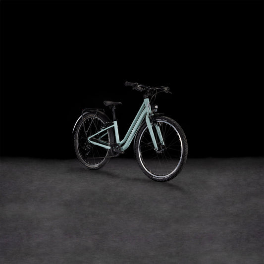 Das CUBE Ella 240 aloegreen'n'white 2025, ein Tiefeinsteigerrahmenrad von CUBE mit schwarzer Bereifung, Shimano 3x8-Schaltung und einem Gepäckträger wird auf einer grauen Fläche vor schwarzem Hintergrund gezeigt.