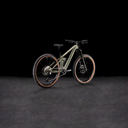 Das CUBE Stereo ONE44 HPC Rookie dustyolive'n'gold 2025 ist ein modernes Mountainbike mit mattem, olivgrünem Carbonrahmen, braunen Schwalbe Nobby Nic-Reifen, Vorderradfederung und robustem Offroad-Design, das sich vor einem dunklen Hintergrund präsentiert.
