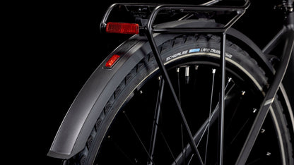 Nahaufnahme des Hinterrads eines CUBE Nature ONE Allroad black'n'black mit schwarzem Schutzblech, Gepäckträger, rotem Reflektor und Schwalbe Land Cruiser Reifen vor schwarzem Hintergrund. Shimano 1x8-Gang Schaltung Komponenten sind auch teilweise sichtbar.