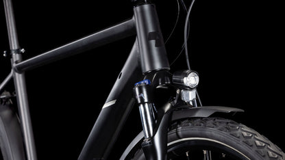 Nahaufnahme der Front des CUBE Nature ONE Allroad black'n'black, die Rahmen, Federgabel, Reifen, Vorderlicht und Schutzblech vor schwarzem Hintergrund hervorhebt. Verfügt über hydraulische Scheibenbremsen für überlegene Bremskraft.