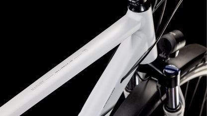 Nahaufnahme des CUBE Nature Pro Allroad cotton'n'grey 2025 mit weißem Aluminiumrahmen mit "NATURE"-Schriftzug auf dem Oberrohr, schwarzem Lenker und Federgabel, vor schwarzem Hintergrund.