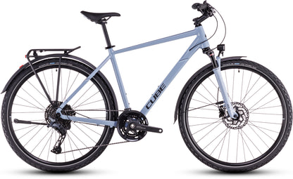 Das CUBE Cube Nature EXC Allroad pigeonblue'n'black ist ein hellblaues Hybridrad mit schwarzem Sitz, Lenker, Gepäckträger und Schutzblechen. Es verfügt über hydraulische Scheibenbremsen, eine Vorderradfederung und einen Shimano Cues 2x11-Gang-Antrieb für Fahrten in der Stadt oder im Gelände.