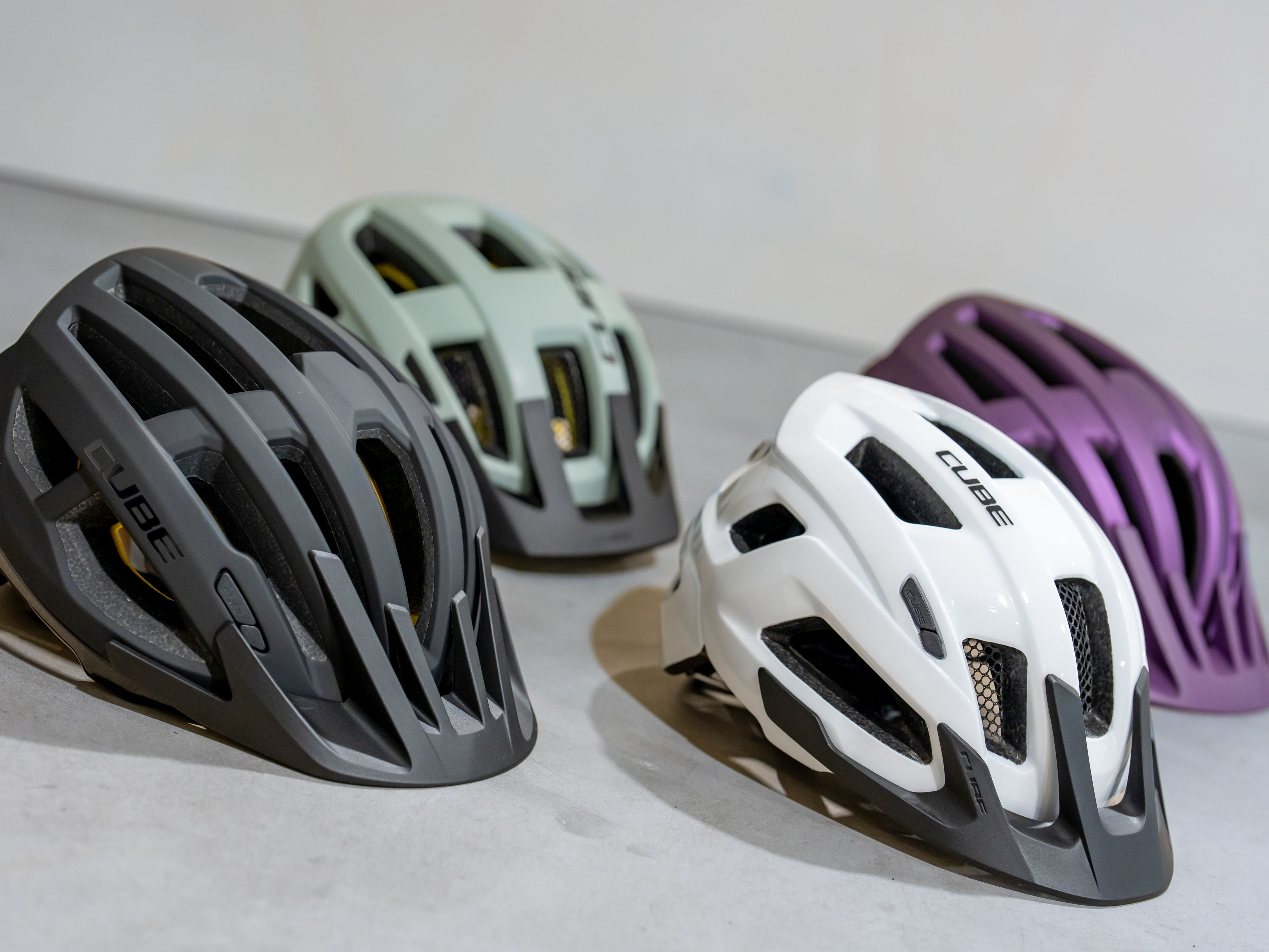 4 Fahrradhelme in verschiedenen Farben auf dem Boden. 