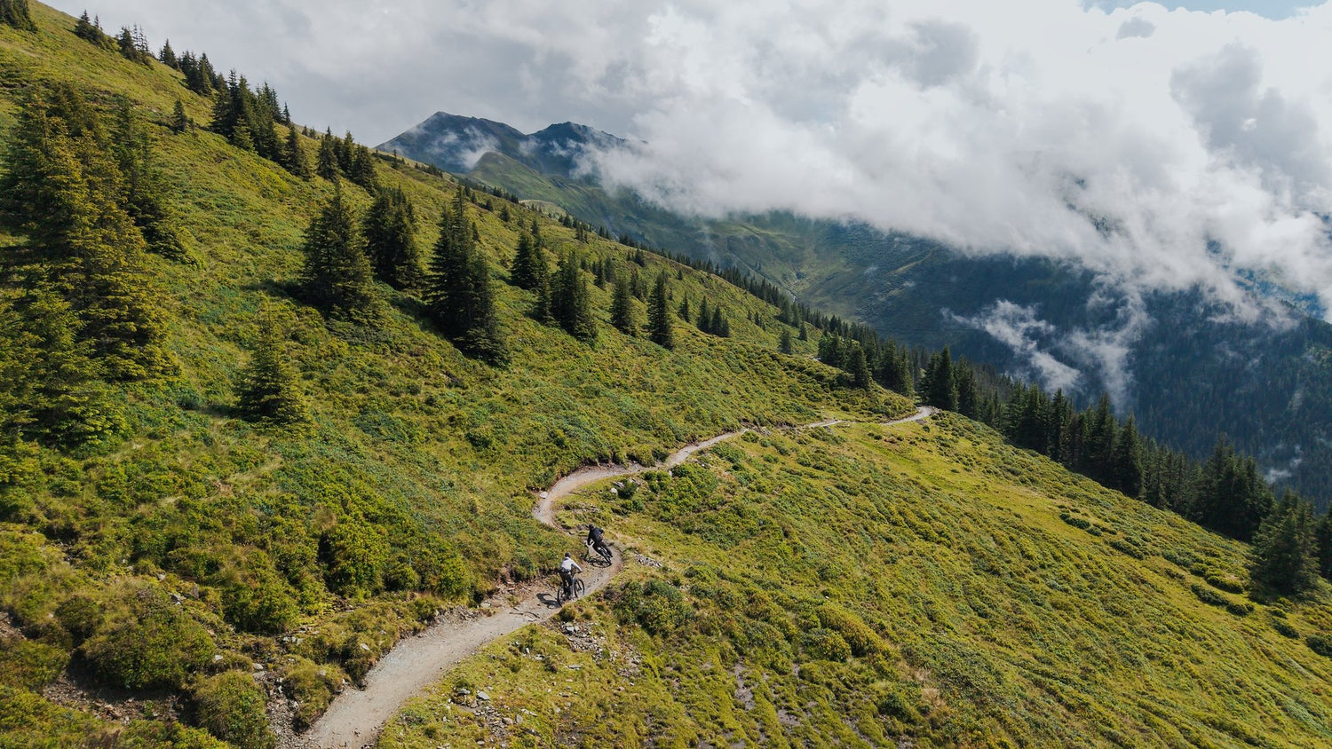 Drohennbild von Landschaft mit 2 Mountainbikern auf einem Trail